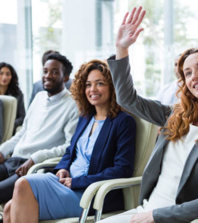 Businesswoman raising hand during meeting in office